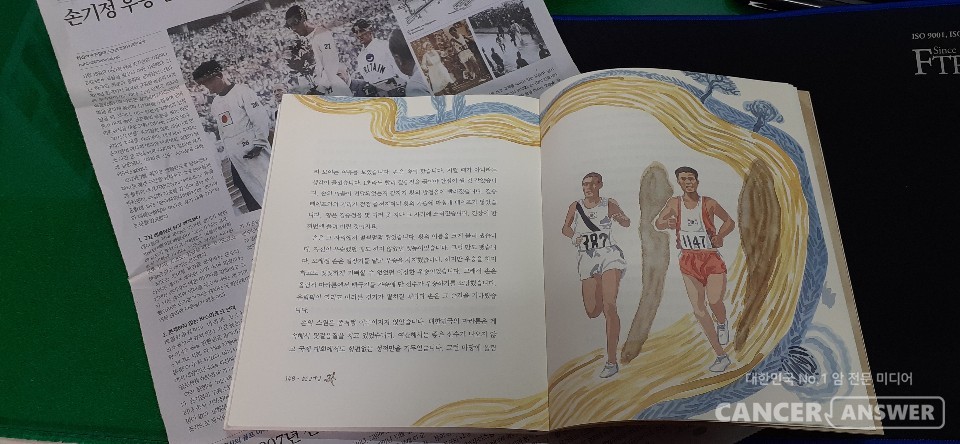 김영 지음 '슬픈 금메달'의 마지막 대목, 바르셀로나의 영웅 황영조가 손기정 선생에게 영광을 돌리는 장면에 사용된 장선환의 상징적 삽화가 아름답다. 뒷배경에는 손기정 사망 11주년 특집으로 제작된 중앙일보 지면.