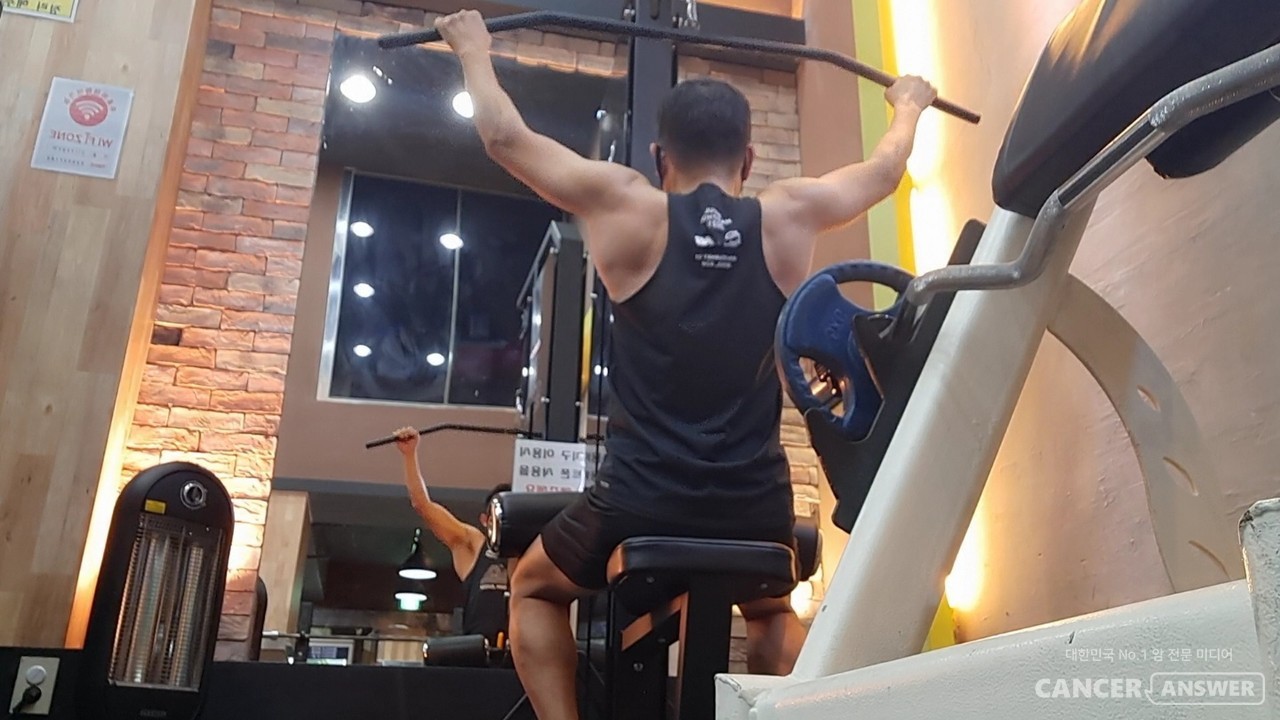 랫풀다운 머신에서 넓게 손을 벌려 잡고 아래로 당겨내리는 운동을 하면, 넓고 강한 활배근을 만들 수 있다./ 캔서앤서DB