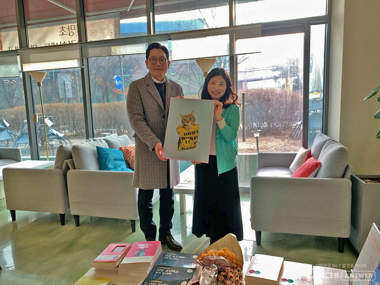 암경험자와 가족들이 모여 만든 캔프협동조합이 예비사회적기업인 후불제 상조회사 예담라이프(대표 신선철)와 함께 진행하는 ‘앎경험자 나의 이야기’ 공모전 첫 수상자가 나왔다. 첫 수상자인 강진경 작가(오른쪽)와 예담라이프 신선철 대표가 공모전 상품인 김희정 색연필아티스트의 작품 'SMILE'을 들고 기념 촬영을 했다./캔서앤서 DB