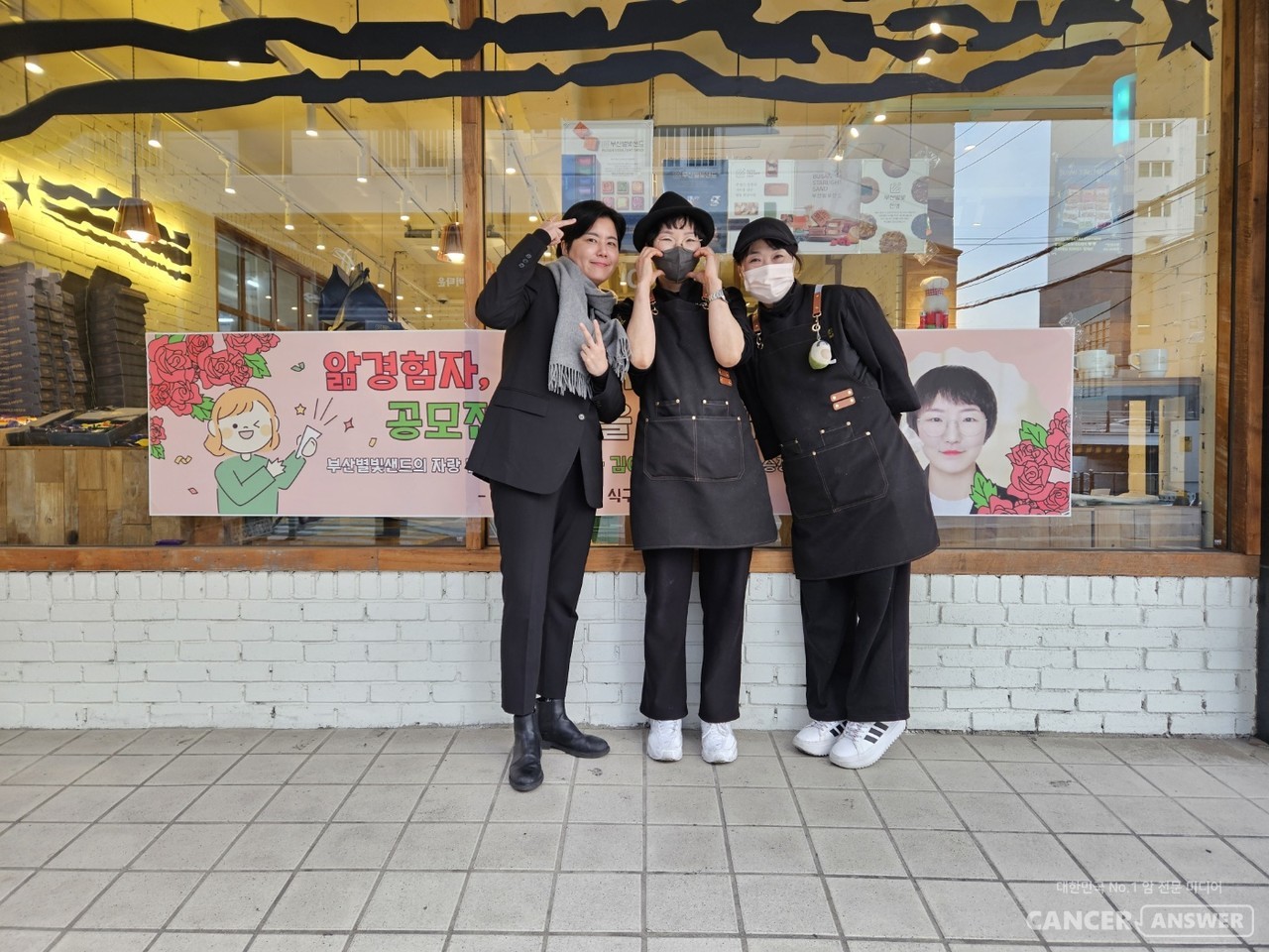 암경험자와 가족들이 모여 만든 캔드림협동조합이 예비사회적기업인 후불제 상조회사 예담라이프(대표 신선철)와 함께 진행하는 ‘앎경험자 나의 이야기’ 공모전 2회 수상자로 난소암 경험자인 김예린 씨가 선정됐다. 김예린 씨(가운데)가 직장인 부산 별빛샌드 베이커리 앞에서 자신의 롤 모델이자 '삶의 원동력'을 준다는 태성당 이나겸 대표(왼쪽), 직장 동료와 함께 당선 기념 촬영을 했다. / 김예린씨 제공