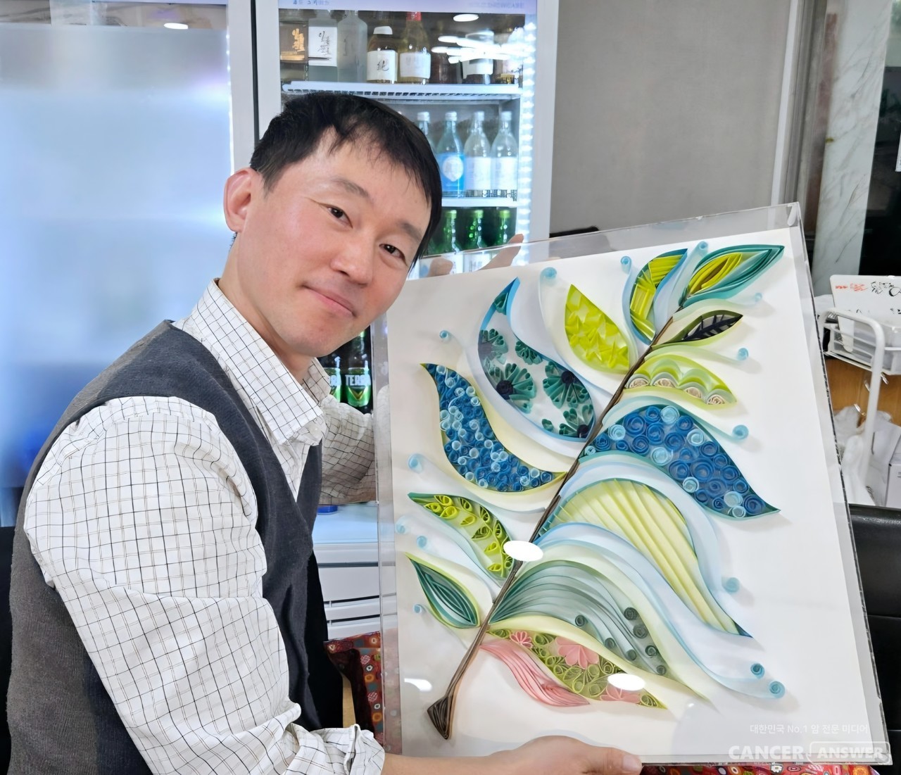 만성골수성백혈병 경험자인 박준호 캔드림협동조합 조합원이 ‘앎경험자 나의 이야기’ 공모전 시상품인 김소라 종이공예 작가의 작품 '희망의 깃털'을 들고 있다./캔드림협동조합 사진 